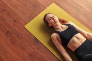 Atemübungen zur Entspannung, Junge Frau entspannt auf Yoga Matte