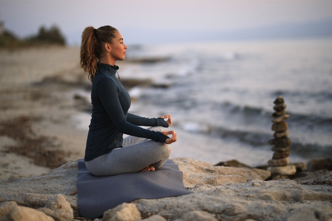 young-woman-meditating-in-lotus-position-on-a-rock; Atemtechniken; Atemübungen; Achtsamkeit; Resilienz